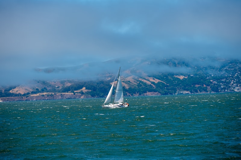 Sailboat on choppy water with misty hills