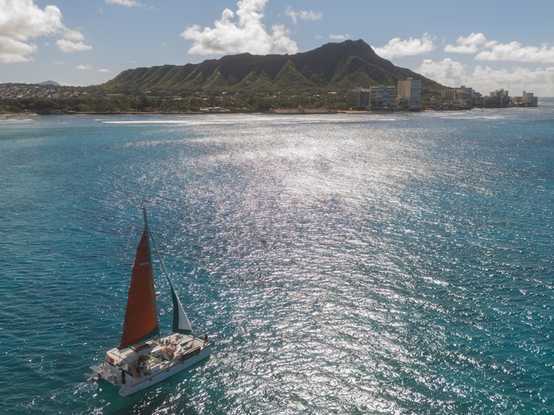 A sailboat sails near diamond head, hawaii.
